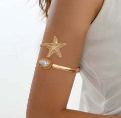 This gold-plated starfish and pearl arm cuff bracelet is often marketed as a boho beach statement piece.