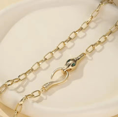 This is a gold-plated snake pendant necklace with green eyes.