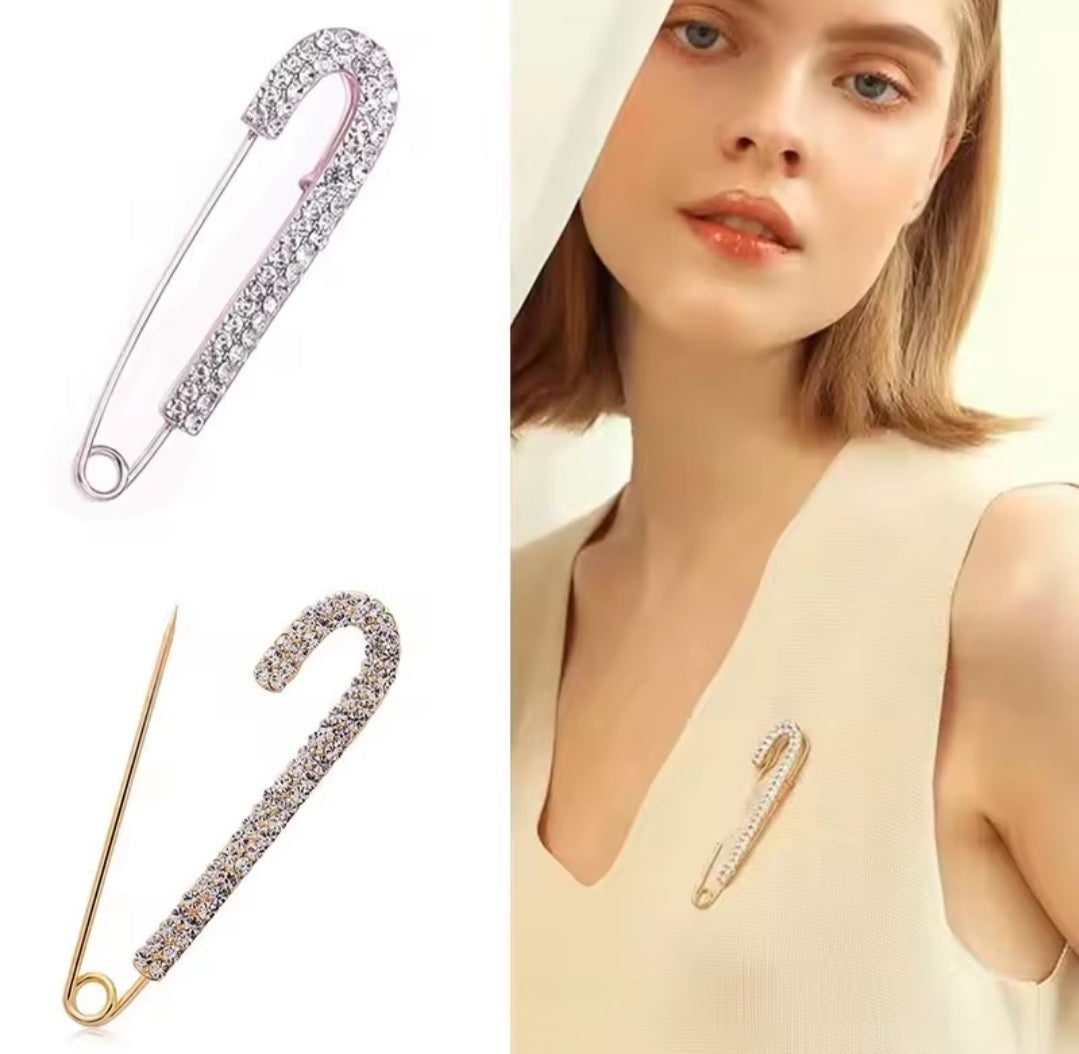 a rhinestone safety pin brooch, often featuring a robust metal base adorned with sparkling crystals.
