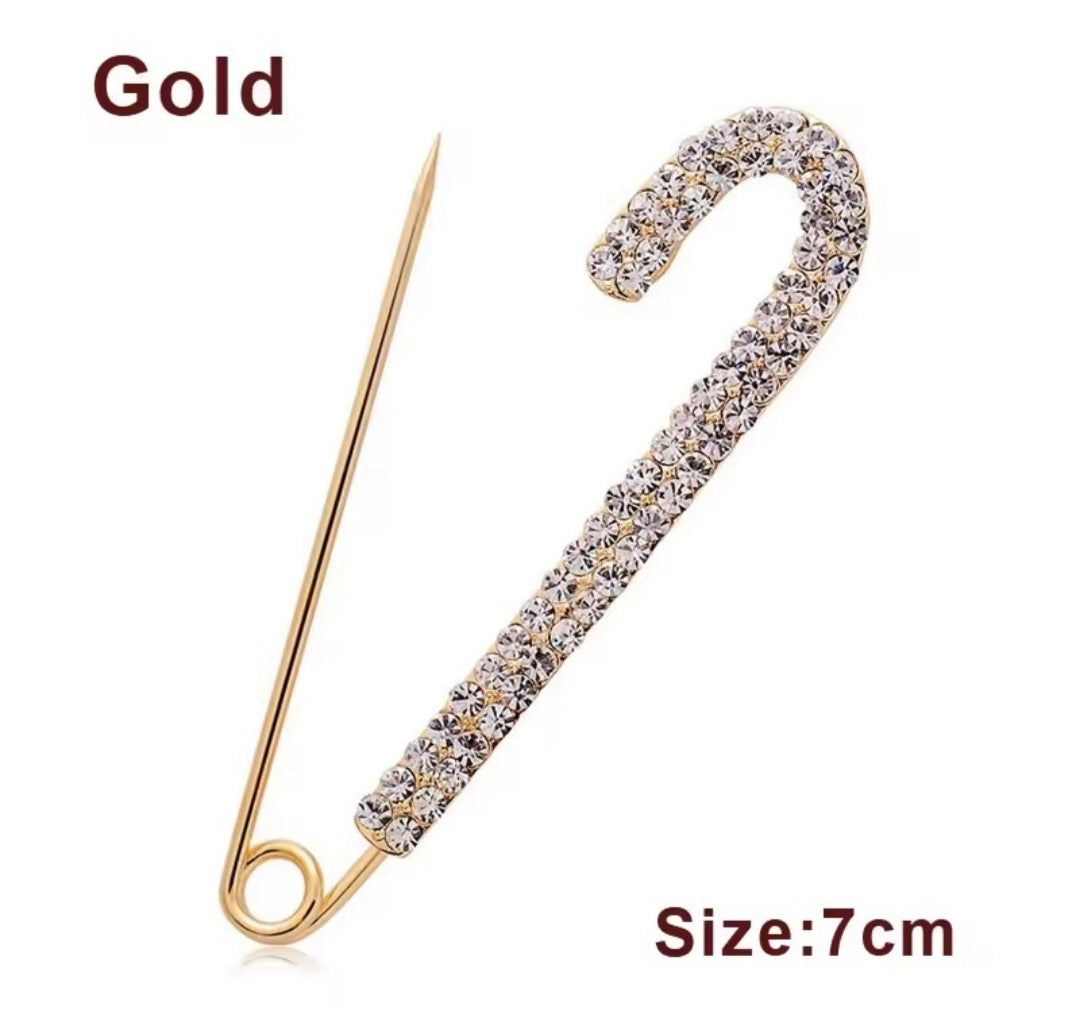 a rhinestone safety pin brooch, often featuring a robust metal base adorned with sparkling crystals.