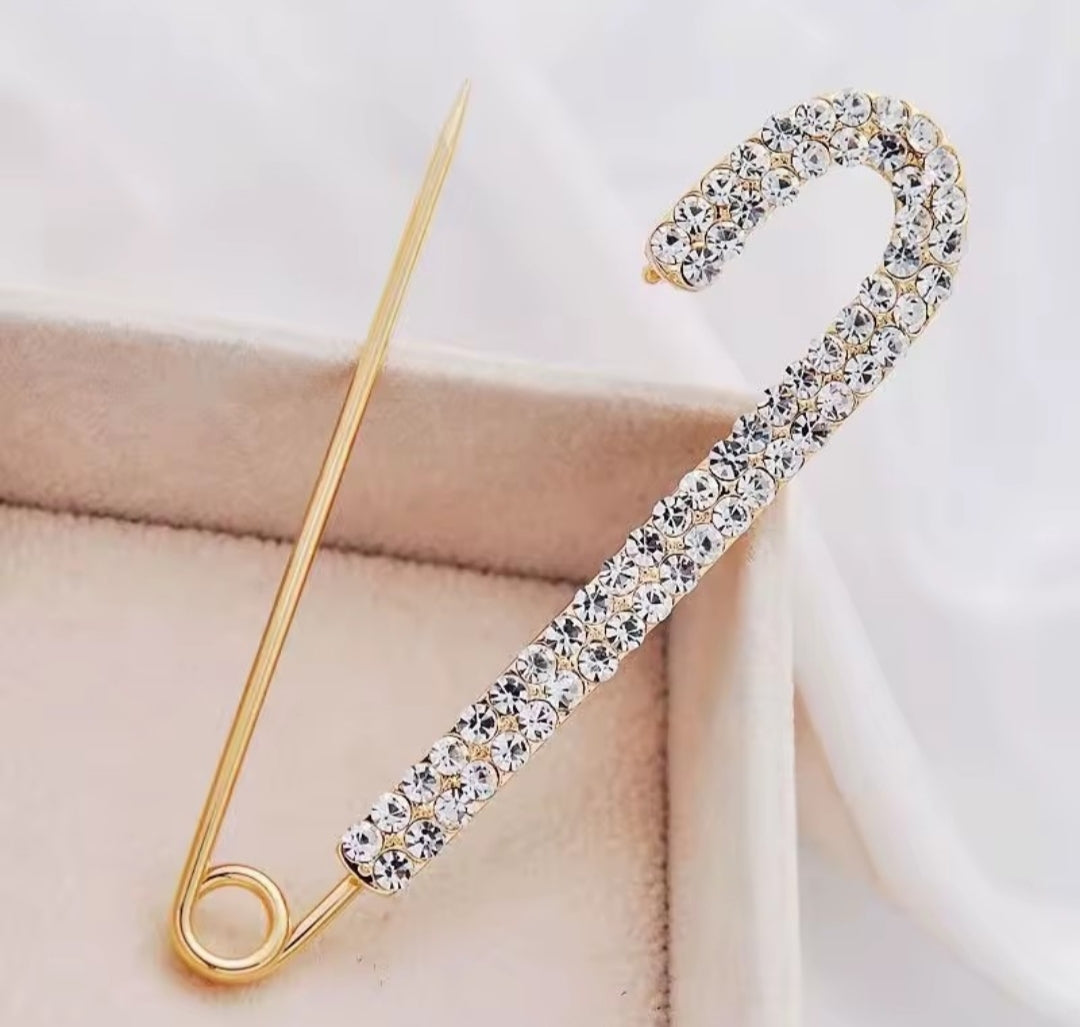 a rhinestone safety pin brooch, often featuring a robust metal base adorned with sparkling crystals.