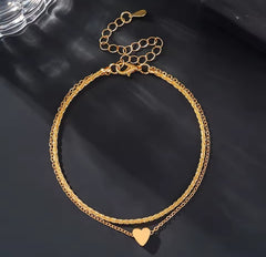 This is a minimalist, gold-plated double-layer ankle bracelet featuring a delicate heart charm and a shimmering chain.