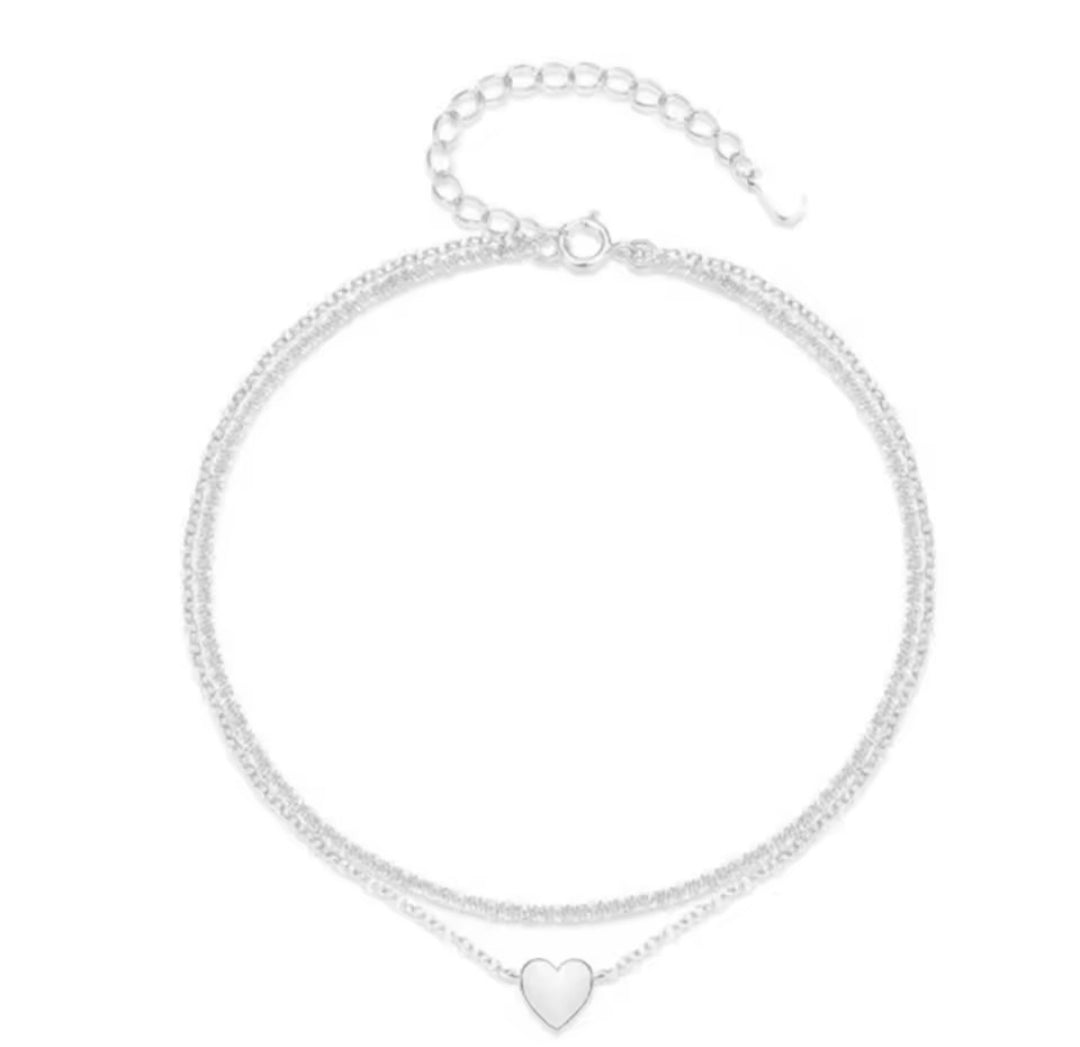 This is a minimalist, silver-plated double-layer ankle bracelet featuring a delicate heart charm and a shimmering chain.