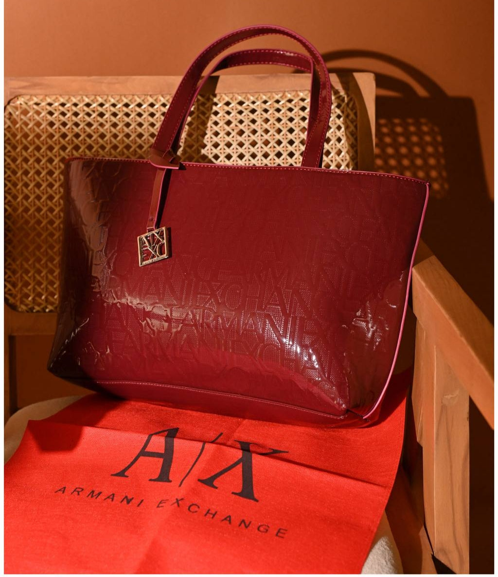 Armani Exchange brand-embossed tote bag in a dark red color and a patent finish.