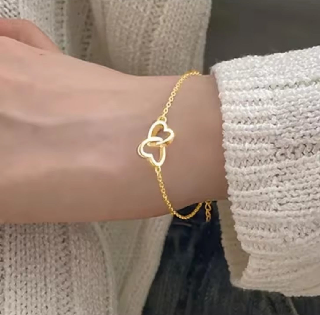 a simple gold interlocking heart charm bracelet, often made of alloy or sterling gold.