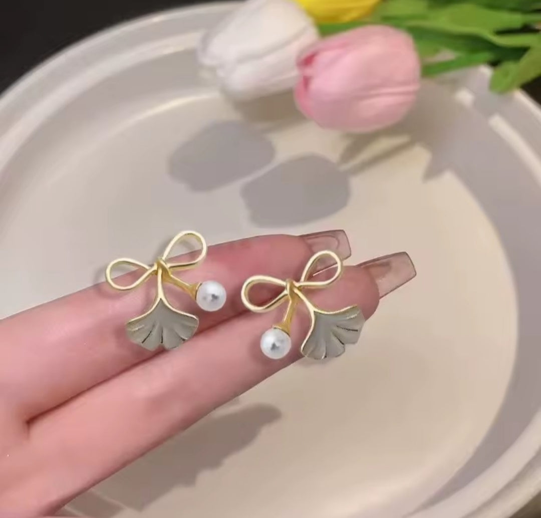 These earrings feature a ginkgo leaf and bowknot design paired with imitation pearls.