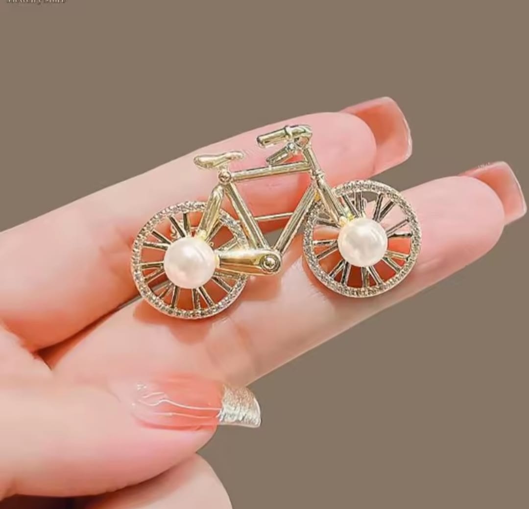 a gold-colored alloy bicycle brooch with faux pearl and rhinestone accents