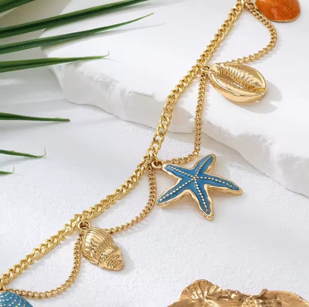 This is a gold-toned, multi-layer women's anklet featuring starfish and shell charms. 