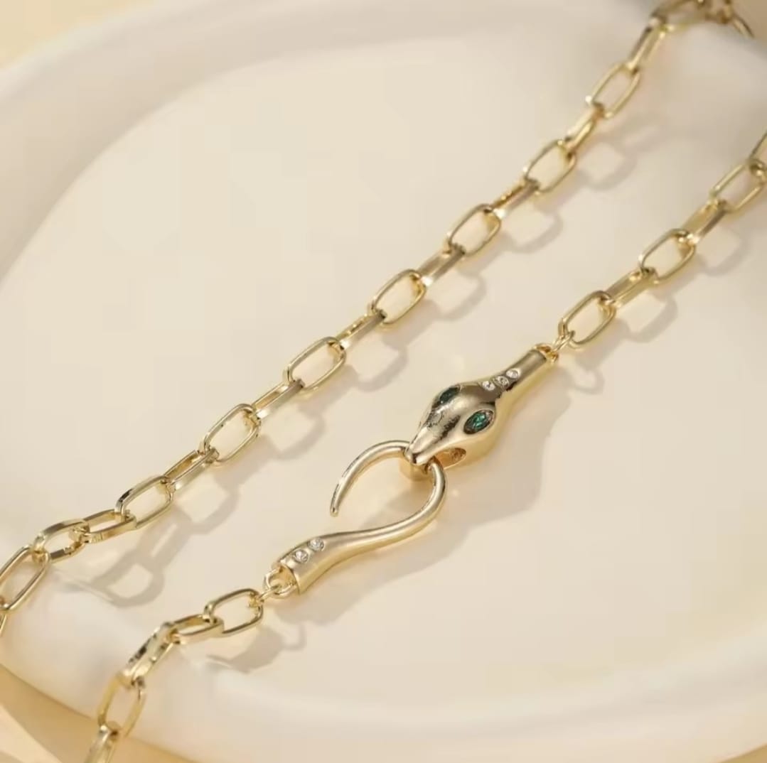 This is a gold-plated snake pendant necklace with green eyes. 