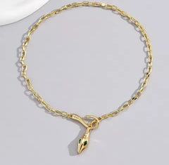 This is a gold-plated snake pendant necklace with green eyes. 