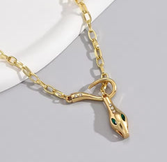 This is a gold-plated snake pendant necklace with green eyes. 